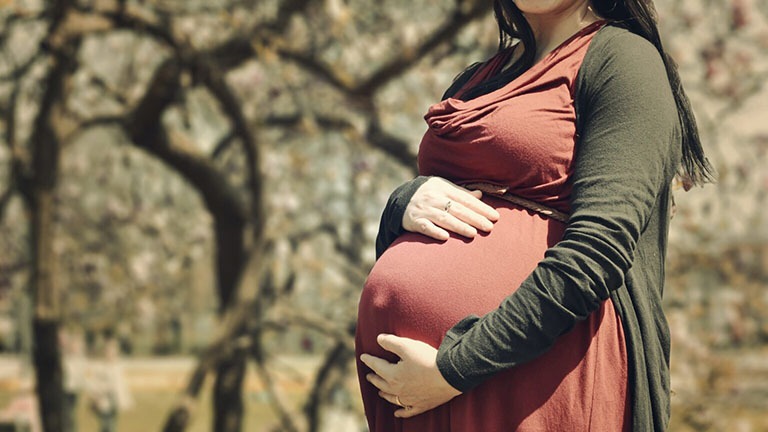 Ventre de femme enceinte debout se tenant le ventre.