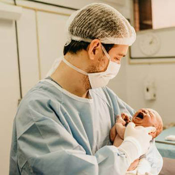 Un père tient dans ses bras son bébé après l'accouchement, après avoir été accompagné par des sages-femmes à Bruxelles.