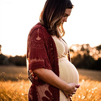 Un femme enceinte accompagnée dans sa grossesse par des sages-femmes à Bruxelles se tient le ventre.